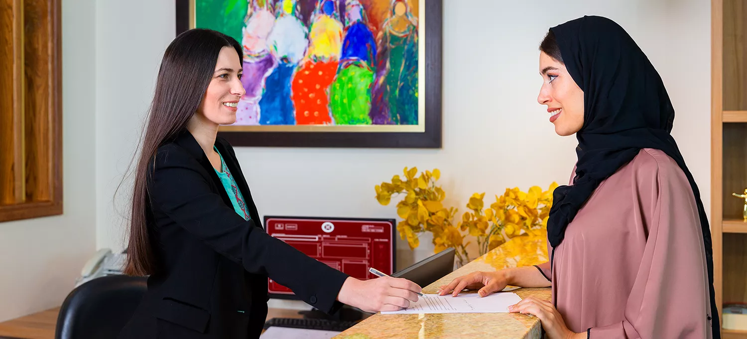Servcorp receptionist handing mail to client. 